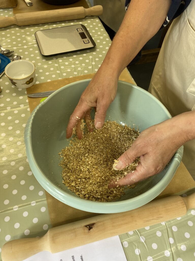 Mixing oatcake dough by hand in a mixing bowl at Bairnkine